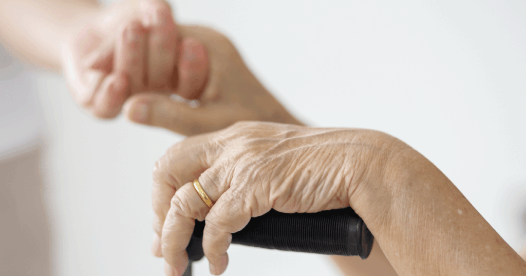 在宅介護の中で支え合いながら歩く高齢者の手元と杖